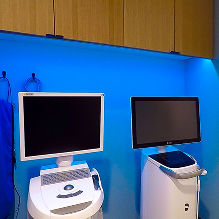 Two computer monitors in front of a blue wall