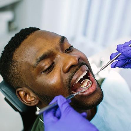 Dentist with blue gloves looking at patient's teeth
