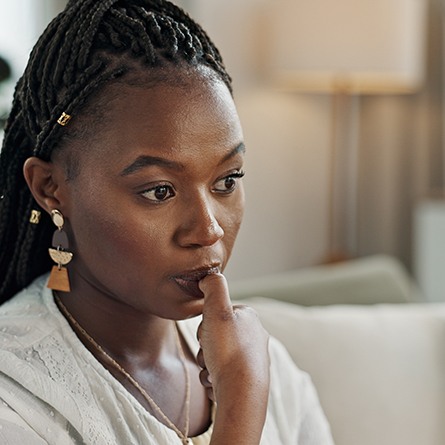 Closeup of woman biting her nails on couch at home